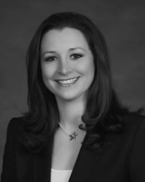 Black and white headshot of Orthodontist Dr. Ali smiling in a blazer over a white top