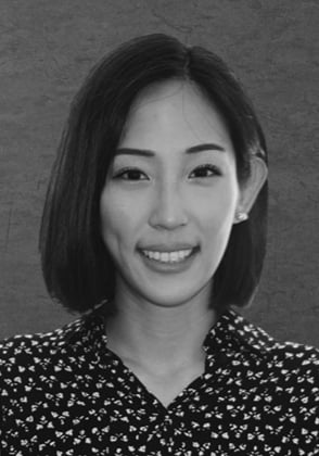 Black and white image of Dr. Le smiling with pearl earrings and a dark patterned shirt