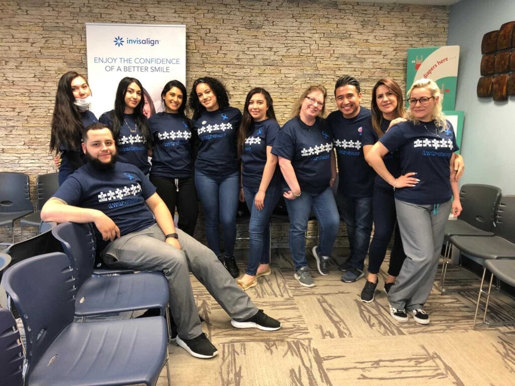 Group of CT Braces team members smiling in the lobby near and invisalign provider advertisement