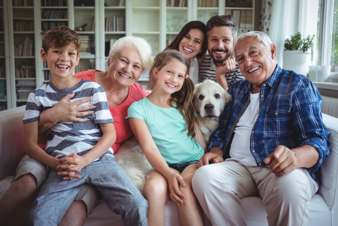 Multigenerational family smiling while posing together on and around a living room couch