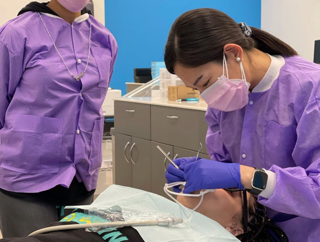 Two orthodontist using orthodontic tools to address an orthodontic emergency in CT