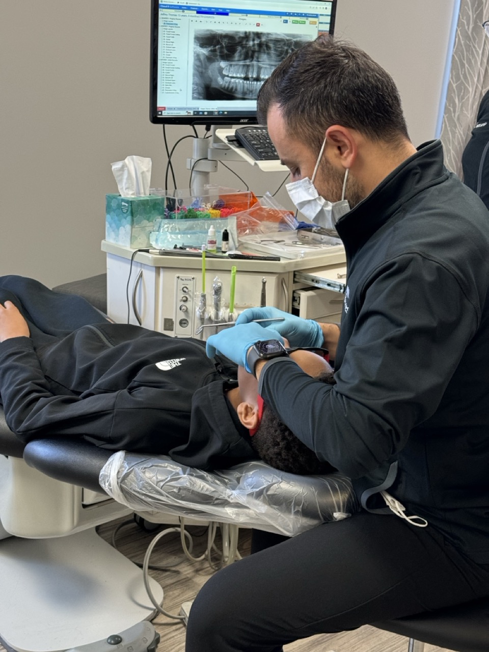 Orthodontist Dr. Fadi Ankah examining a young patient’s braces in New Haven, CT