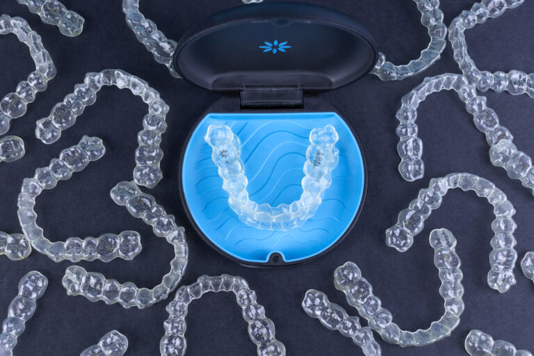 Invisalign® aligners in Danbury, CT spread across a dark blue surface