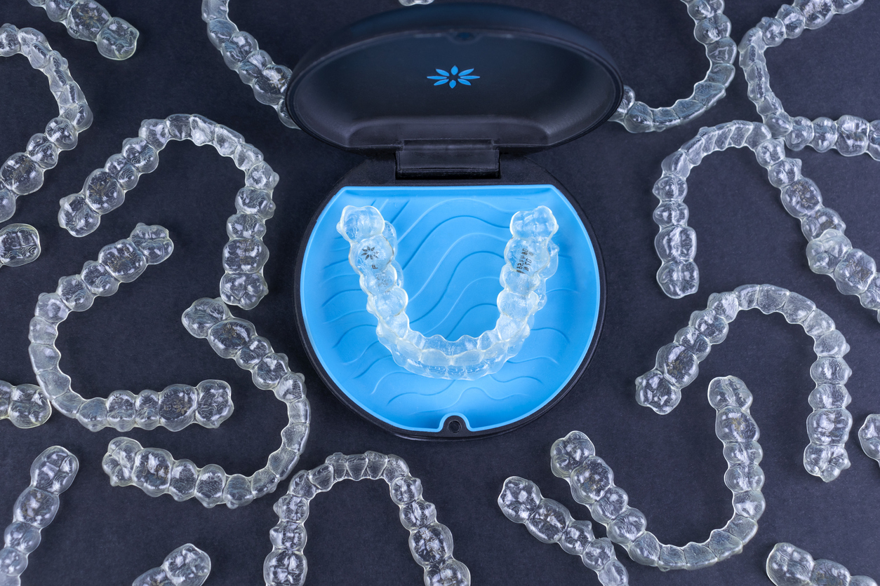 Invisalign® aligners in Danbury, CT spread across a dark blue surface