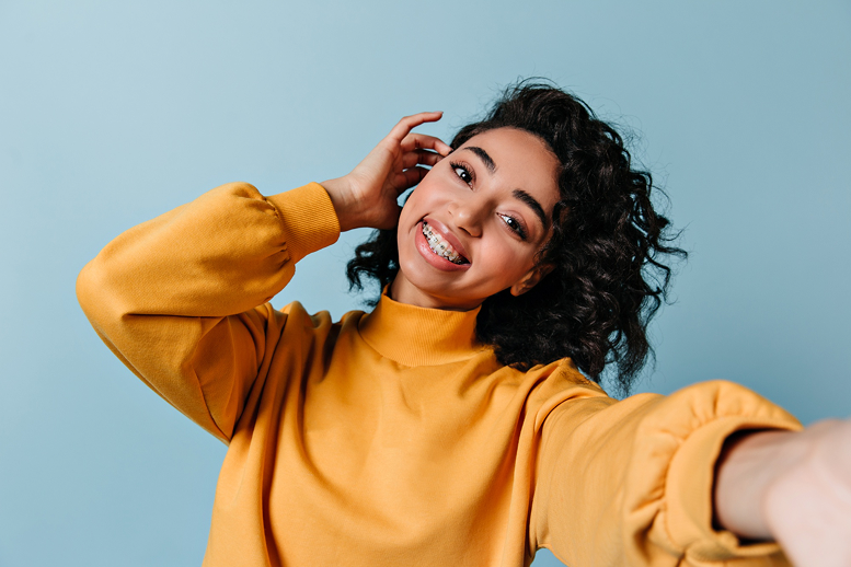 Beautiful young woman with vibrant curly hair smiling with braces in Orange, CT