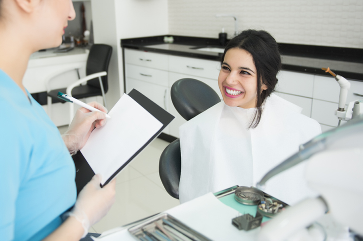 A smiling woman sits comfortably in a dental chair, looking relaxed and at ease during her dental appointment.